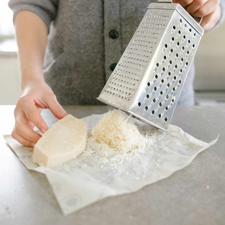 Parmesan cheese being grated onto an Abeego food wrap.
