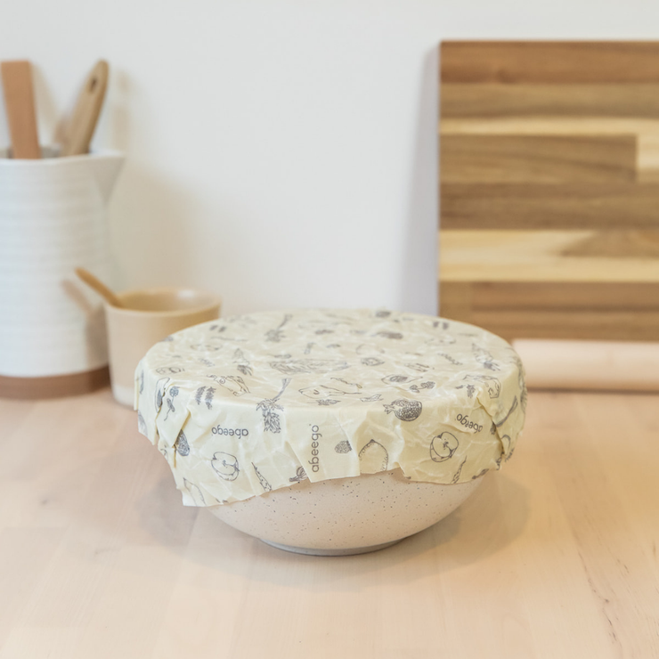 One large square of Abeego reusable beeswax food wrap covering a salad bowl.