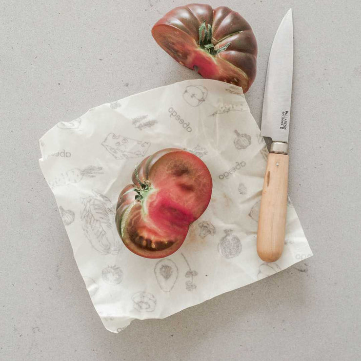 A half cut tomato on an Abeego beeswax wrap.