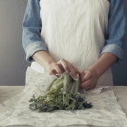 A woman wrapping a head of celery in an Abeego large rectangle beeswax food wrap.