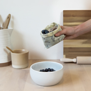 A small rectangular Abeego food wrap dishing blueberries into a bowl.