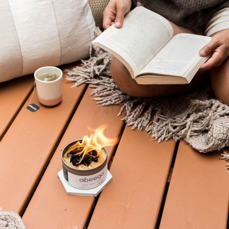 A mini campfire burning while  someone reads and drinks tea in a cozy setting.